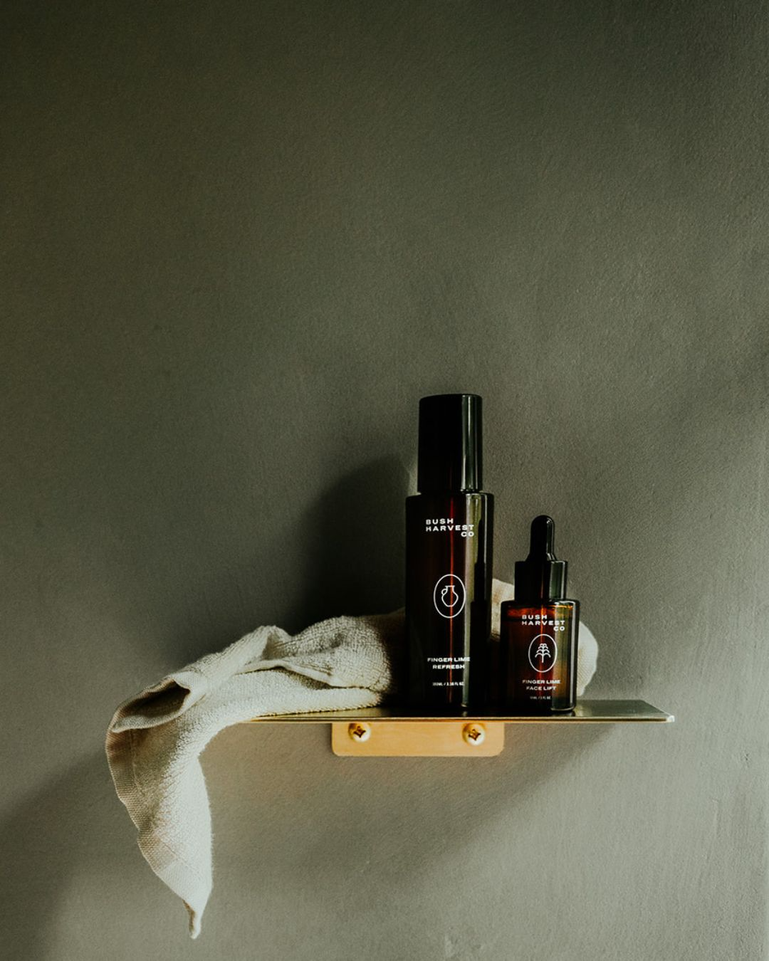 Clean Slate & Glow Kit on brushed gold shower shelf. Finger Lime Refresh Purifying Facial Cleanser, Finger Lime Face Lift Hydrating & Brightening Serum and a resuable, bamboo cotton blend Facial Cleansing Cloth.
