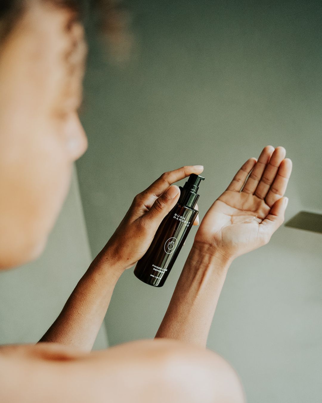 Woman dispensing Finger Lime Refresh Purifying Facial Cleanser into hand.