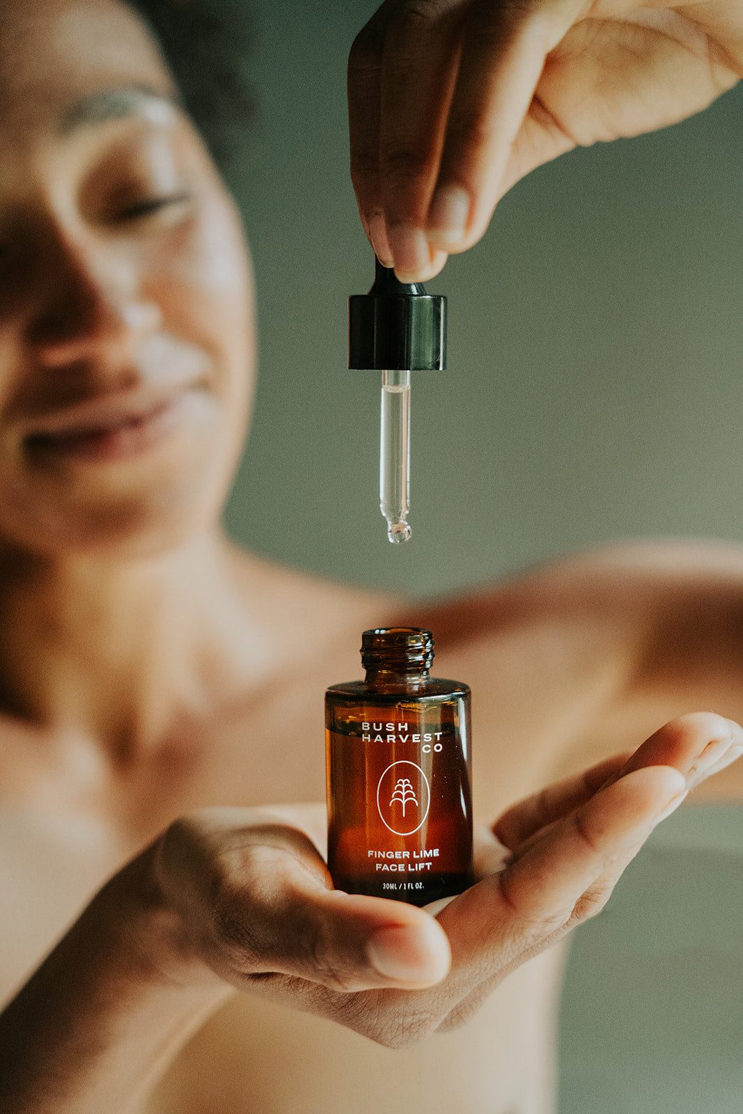 Woman holding dropper and dropping Finger Lime Face Lift Hydrating & Brightening Serum into bottle.